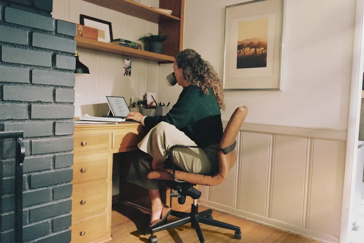 Woman working at a laptop on a wooden desk in a home office