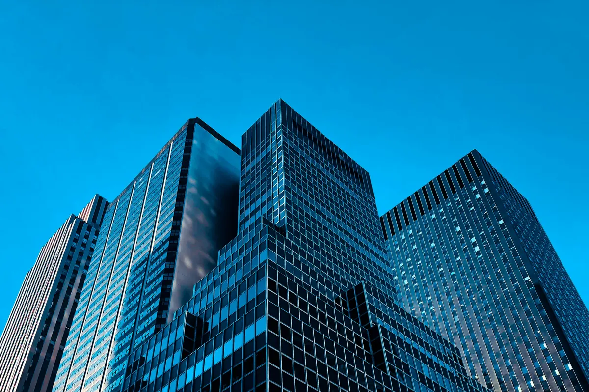 Glass office towers seen from below against a blue sky
